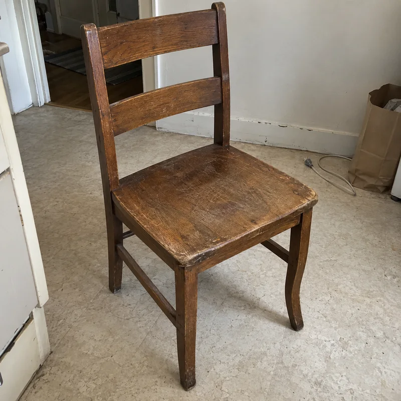 Studio concept: phone photo of an old scratched chair with a crooked right leg