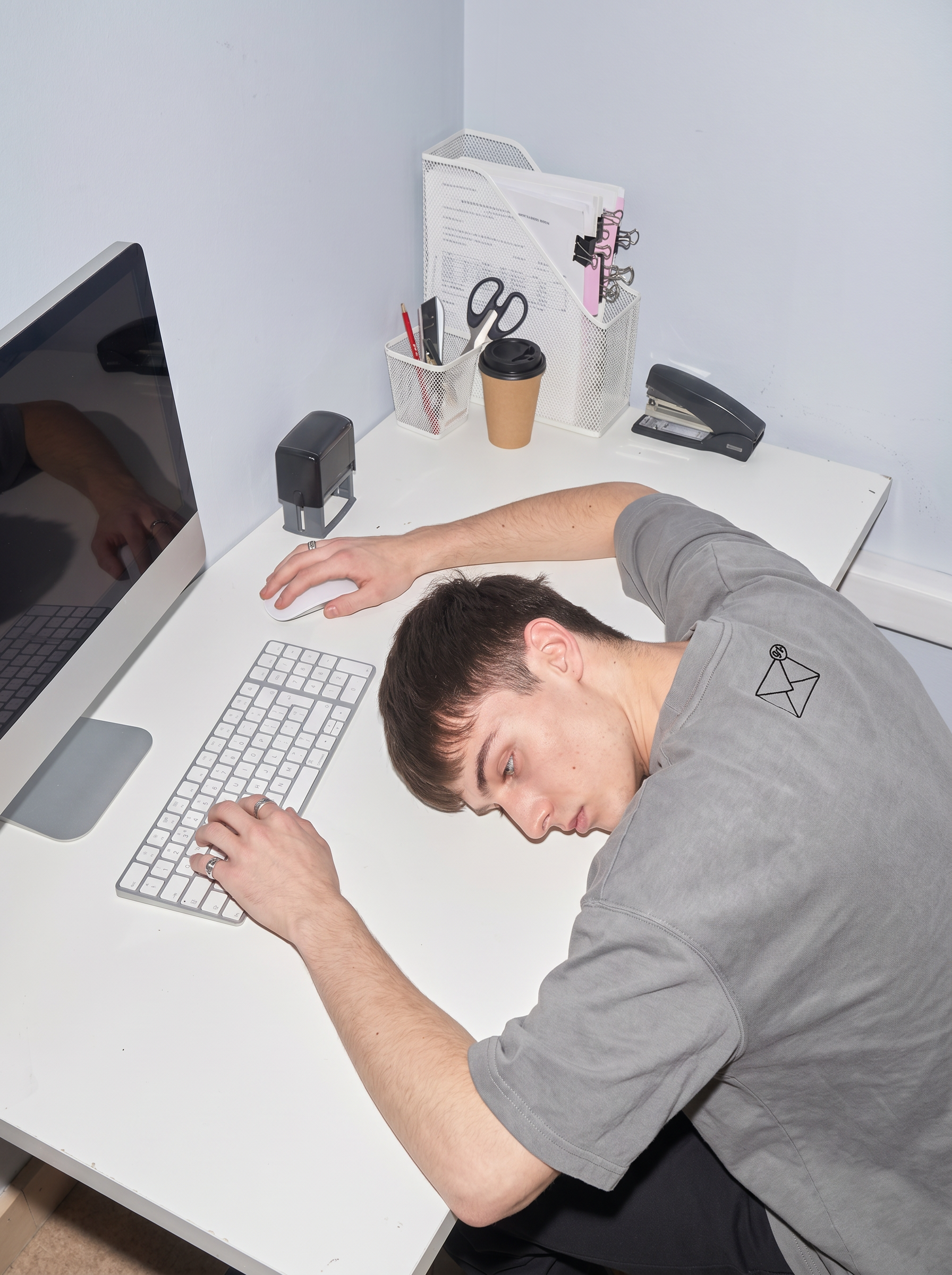 exhausted slumped over table with t shirt behind 99+ emails